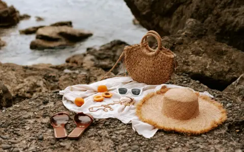 Accesorios de playa: sombrero, bolso, chanclas, gafas de sol y albaricoques, ideales para saber como mantener el moreno de playa.