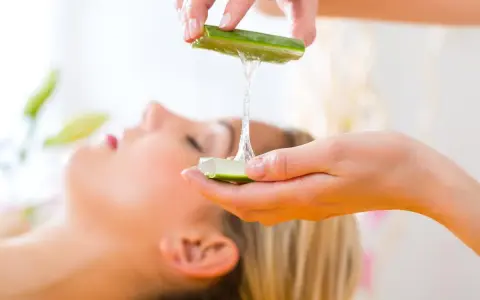 Manos aplicando gel de aloe vera para la cara de una mujer, un tratamiento natural para la piel.