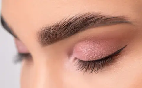 Ojo cerrado con sombra rosa, delineado cat eye y cejas separadas bien definidas.