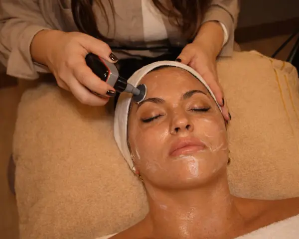 Una mujer recibe un tratamiento facial con un dispositivo de radiofrecuencia. El protocolo radiofrecuencia facial se aplica para rejuvenecer la piel.