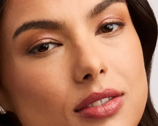 Rostro de mujer con un sutil maquillaje nude, resaltando sus ojos y labios con un toque natural y elegante.