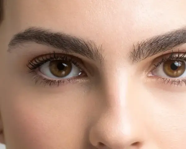 Ojos marrones y cejas pobladas, un ejemplo de cómo dar forma a las cejas para un look natural y definido.
