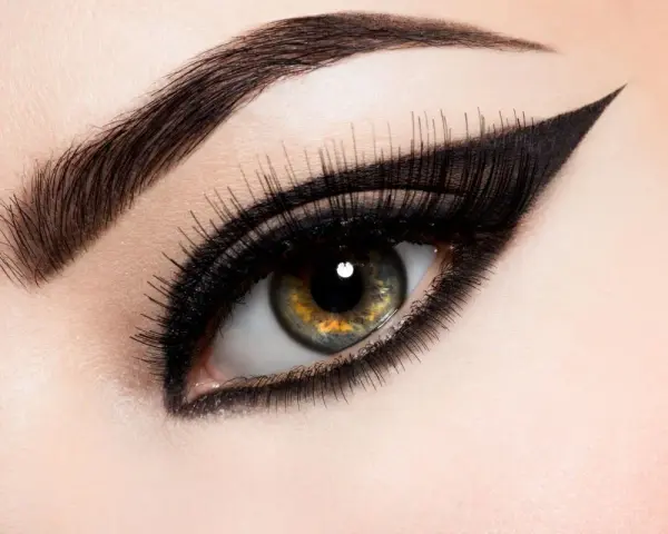 Ojo con maquillaje dramático, cejas definidas y un audaz delineado cat eye.