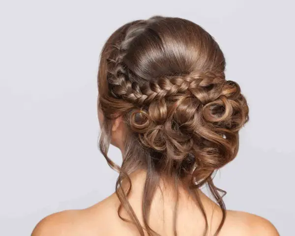 Peinado de novia con trenzas y rizos sueltos, un look romántico y elegante para tu gran día.