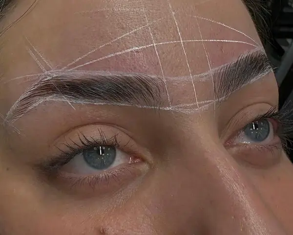 Ojos azules con cejas rectas marcadas con líneas blancas para un diseño perfecto.