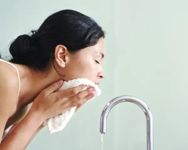 Mujer se limpia el rostro con una toalla suave, como si el agua micelar se enjuaga.