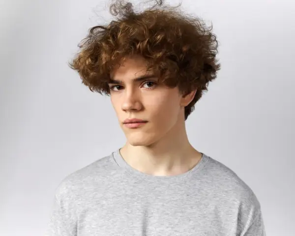 Joven con un moderno corte de pelo rizado hombre, luciendo un estilo desenfadado y juvenil.