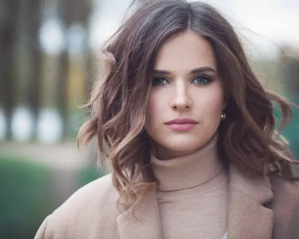 Mujer con peinados media melena elegantes, ondas suaves y un abrigo beige.