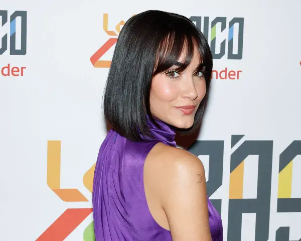 Mujer con un elegante corte de pelo bob con flequillo, luciendo un vestido morado brillante.