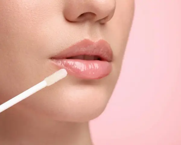 Labios brillantes y jugosos con un aplicador de gloss. El gloss da un acabado húmedo y voluminoso.