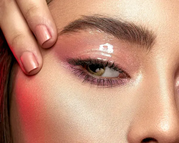 Ojo con maquillaje rosa brillante y cejas laminadas. ¿Cuánto dura el laminado de cejas?