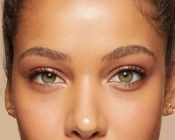 Primer plano de unos ojos verdes y marrones, mostrando cómo cambiar la forma de las cejas con maquillaje.