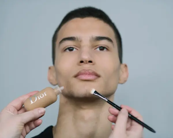 Aplicación de maquillaje hombre con base Dior y brocha.