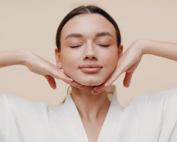 Mujer con ojos cerrados y manos en el rostro, practicando ejercicios faciales para flacidez cara.