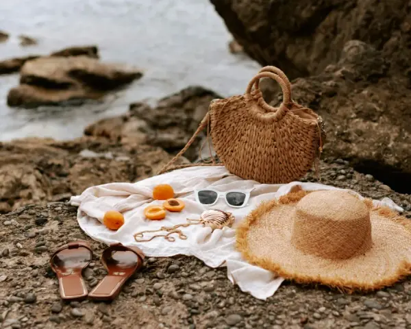 Accesorios de playa: sombrero, bolso, chanclas, gafas de sol y albaricoques, ideales para saber como mantener el moreno de playa.