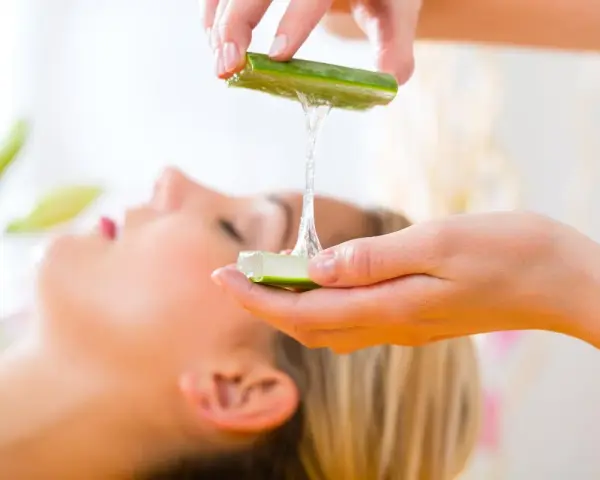 Manos aplicando gel de aloe vera para la cara de una mujer, un tratamiento natural para la piel.