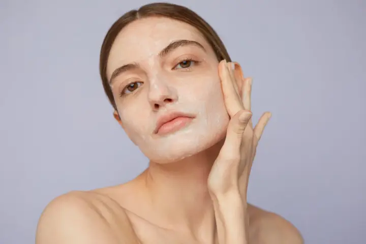 Mujer aplicándose crema para saber como exfoliar la piel. Suave masaje facial para una piel radiante.