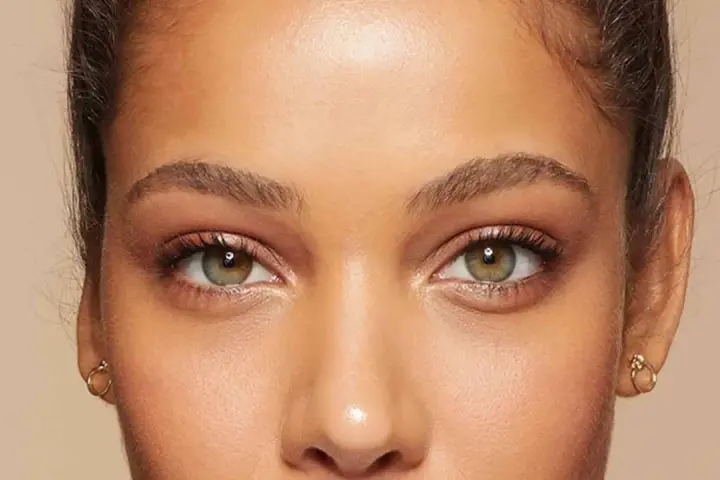 Primer plano de unos ojos verdes y marrones, mostrando cómo cambiar la forma de las cejas con maquillaje.