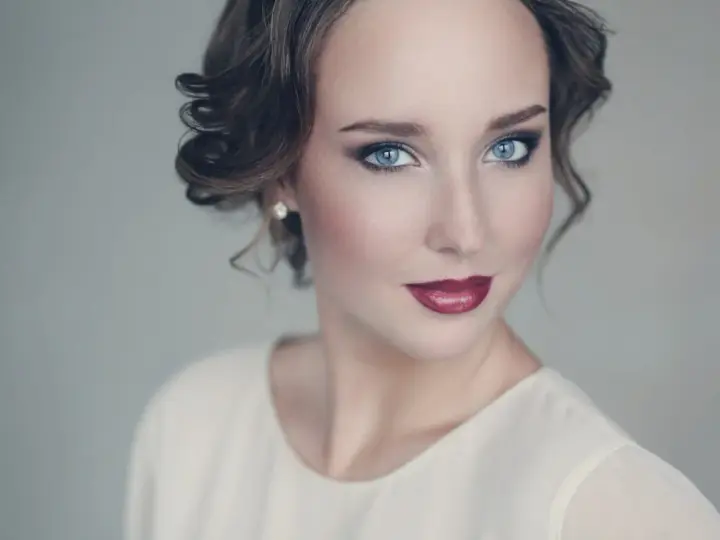 Maquillaje para vestido blanco: ojos ahumados y labios rojos intensos, peinado recogido con rizos.