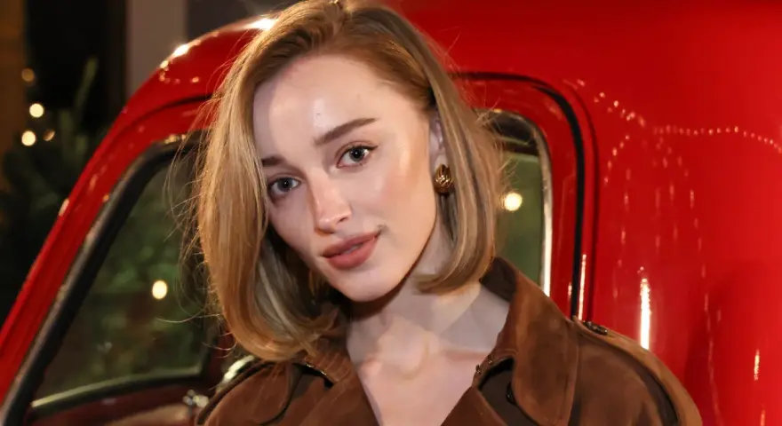 Primer plano de una mujer con maquillaje natural, destacando las partes de las cejas y un labial nude, frente a un vehículo rojo brillante.