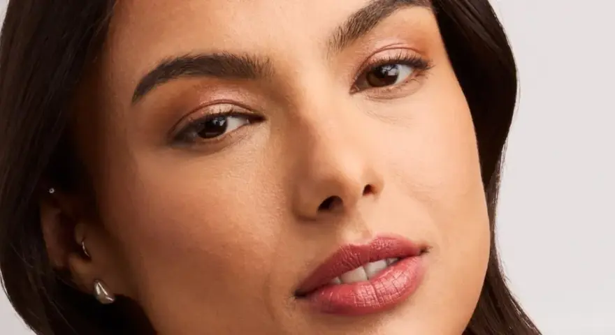 Rostro de mujer con un sutil maquillaje nude, resaltando sus ojos y labios con un toque natural y elegante.