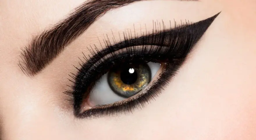 Ojo con maquillaje dramático, cejas definidas y un audaz delineado cat eye.