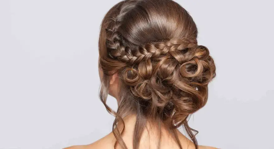 Peinado de novia con trenzas y rizos sueltos, un look romántico y elegante para tu gran día.