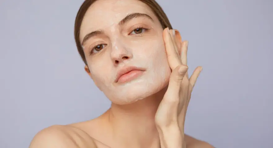 Mujer aplicándose crema para saber como exfoliar la piel. Suave masaje facial para una piel radiante.
