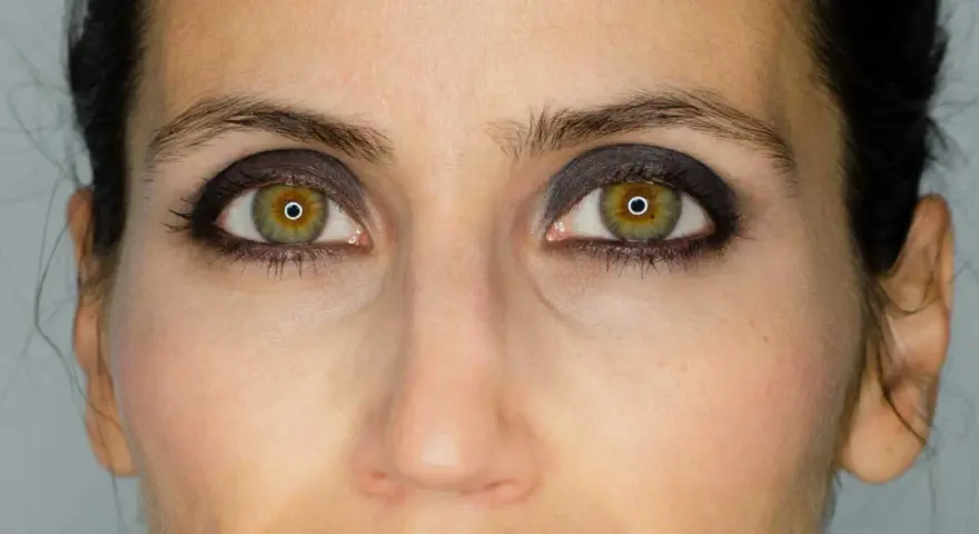 Ojos verdes con un intenso maquillaje negro, resaltando la mirada.