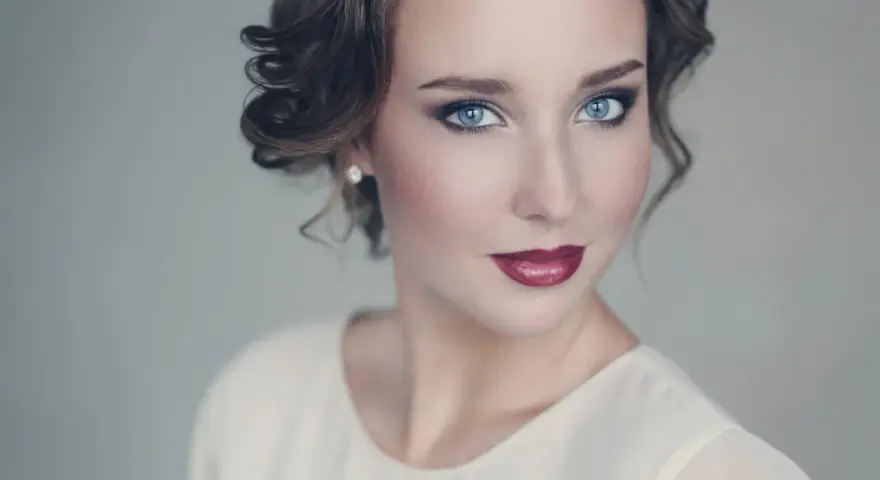 Maquillaje para vestido blanco: ojos ahumados y labios rojos intensos, peinado recogido con rizos.