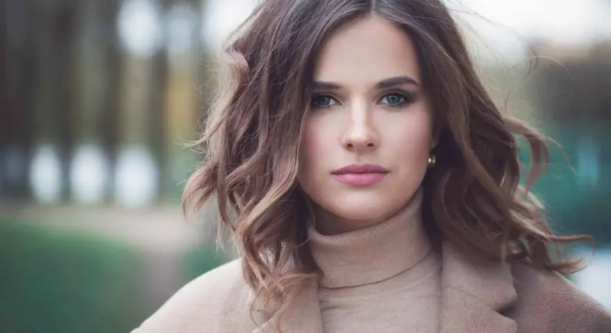 Mujer con peinados media melena elegantes, ondas suaves y un abrigo beige.