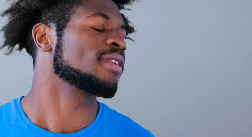 Hombre con perilla barba y ojos cerrados, disfrutando un momento de paz.