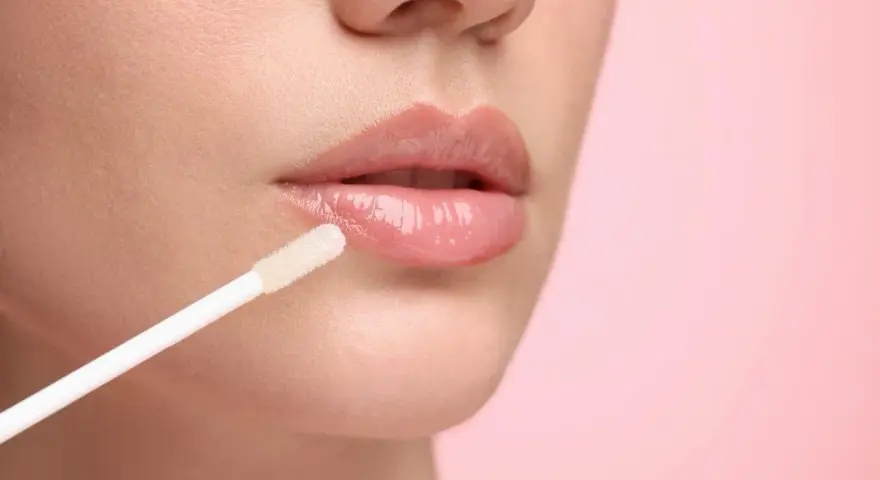 Labios brillantes y jugosos con un aplicador de gloss. El gloss da un acabado húmedo y voluminoso.
