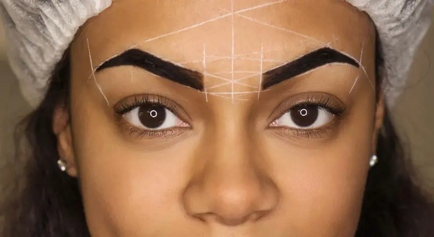 Ojos y cejas marcadas con líneas blancas para diseño. Se observa una posible alergia a la henna en las cejas.