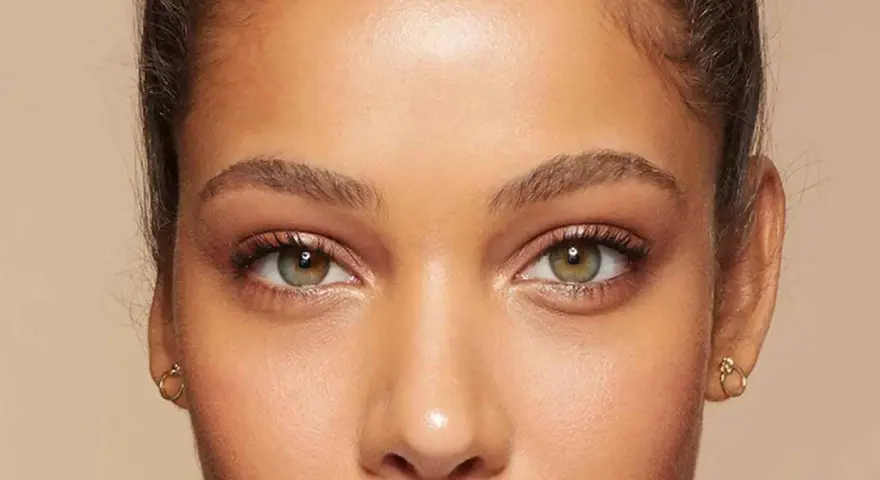 Primer plano de unos ojos verdes y marrones, mostrando cómo cambiar la forma de las cejas con maquillaje.