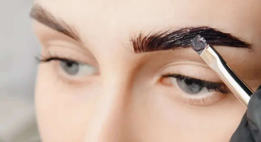 Aplicando tinte oscuro para que se puedan teñir las cejas y darles más definición.