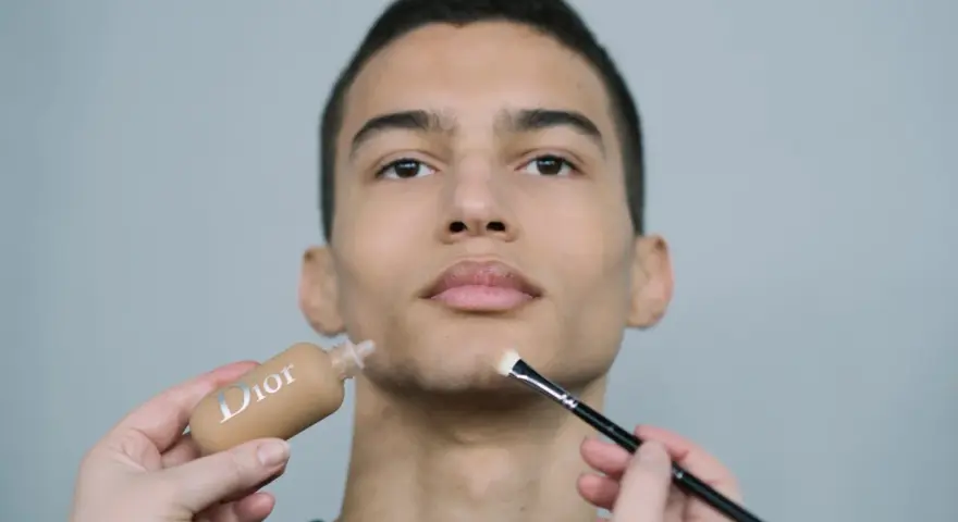 Aplicación de maquillaje hombre con base Dior y brocha.