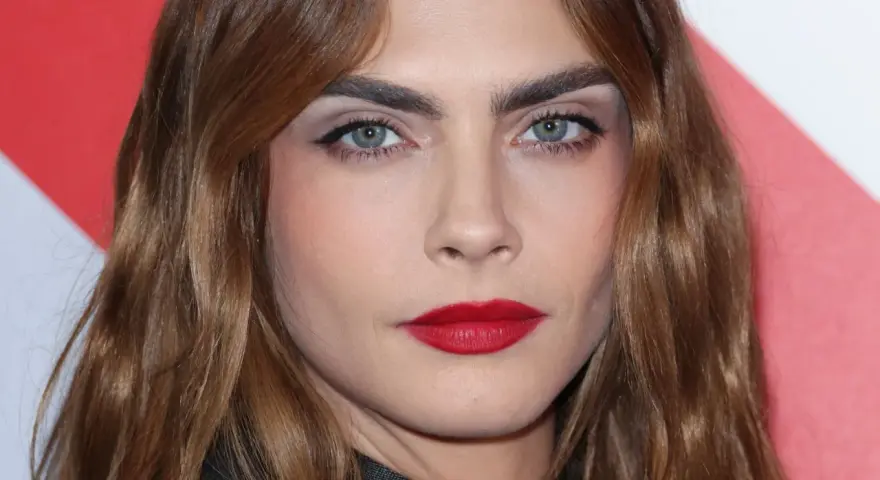 Primer plano de una mujer con cejas pobladas y labios rojos. ¿Recortar cejas sí o no? La decisión es tuya.