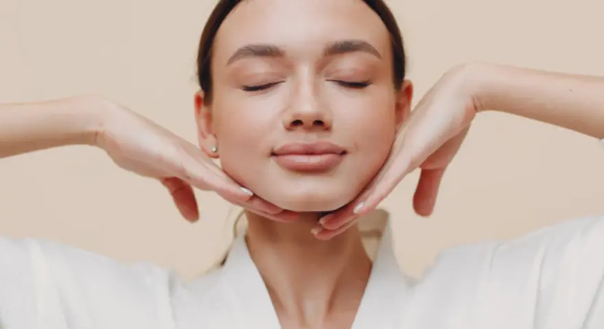 Mujer con ojos cerrados y manos en el rostro, practicando ejercicios faciales para flacidez cara.