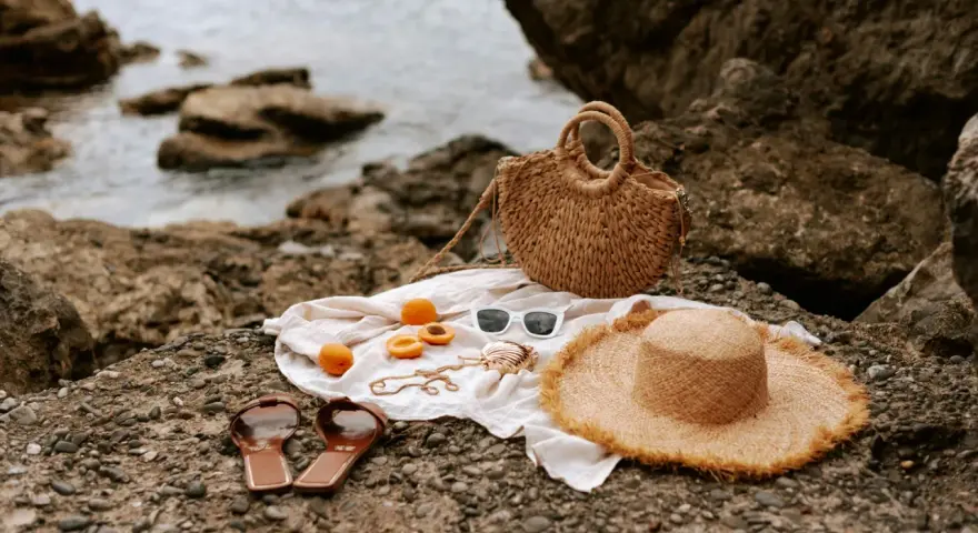 Accesorios de playa: sombrero, bolso, chanclas, gafas de sol y albaricoques, ideales para saber como mantener el moreno de playa.