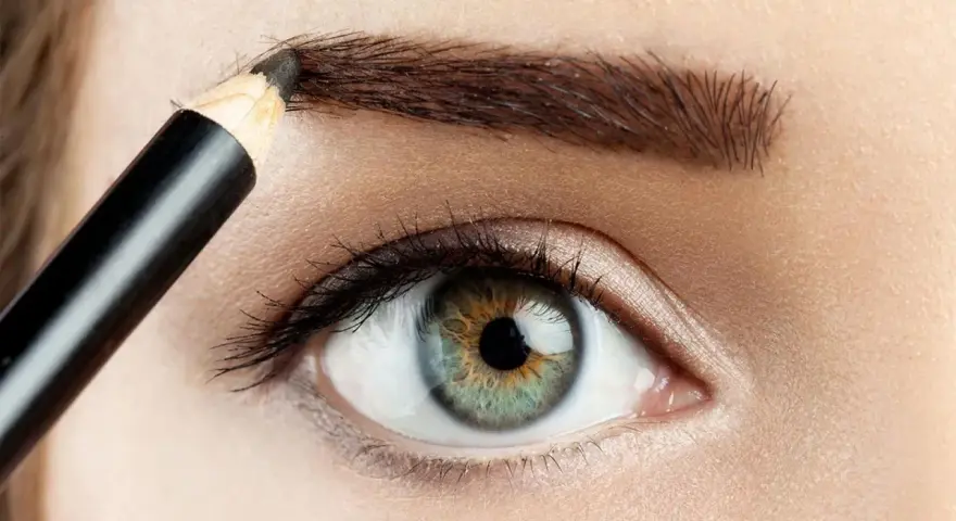 Detalle de ojo y ceja siendo maquillada con lápiz para disimular calvas.