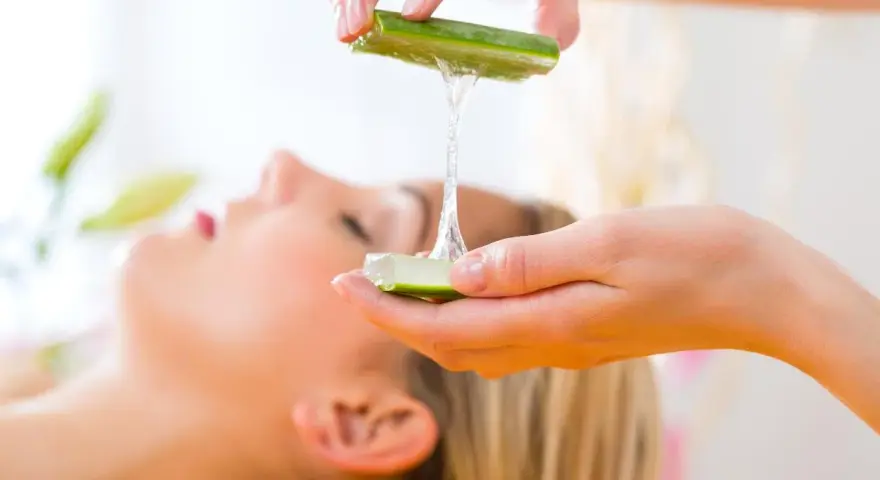 Manos aplicando gel de aloe vera para la cara de una mujer, un tratamiento natural para la piel.