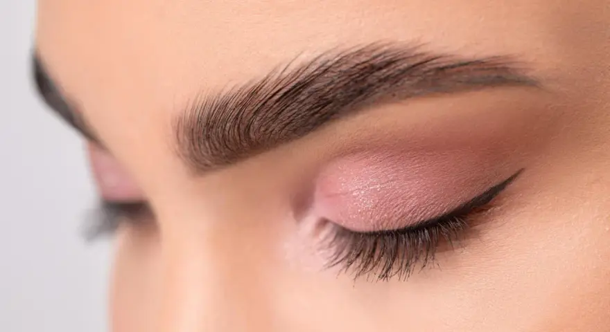 Ojo cerrado con sombra rosa, delineado cat eye y cejas separadas bien definidas.