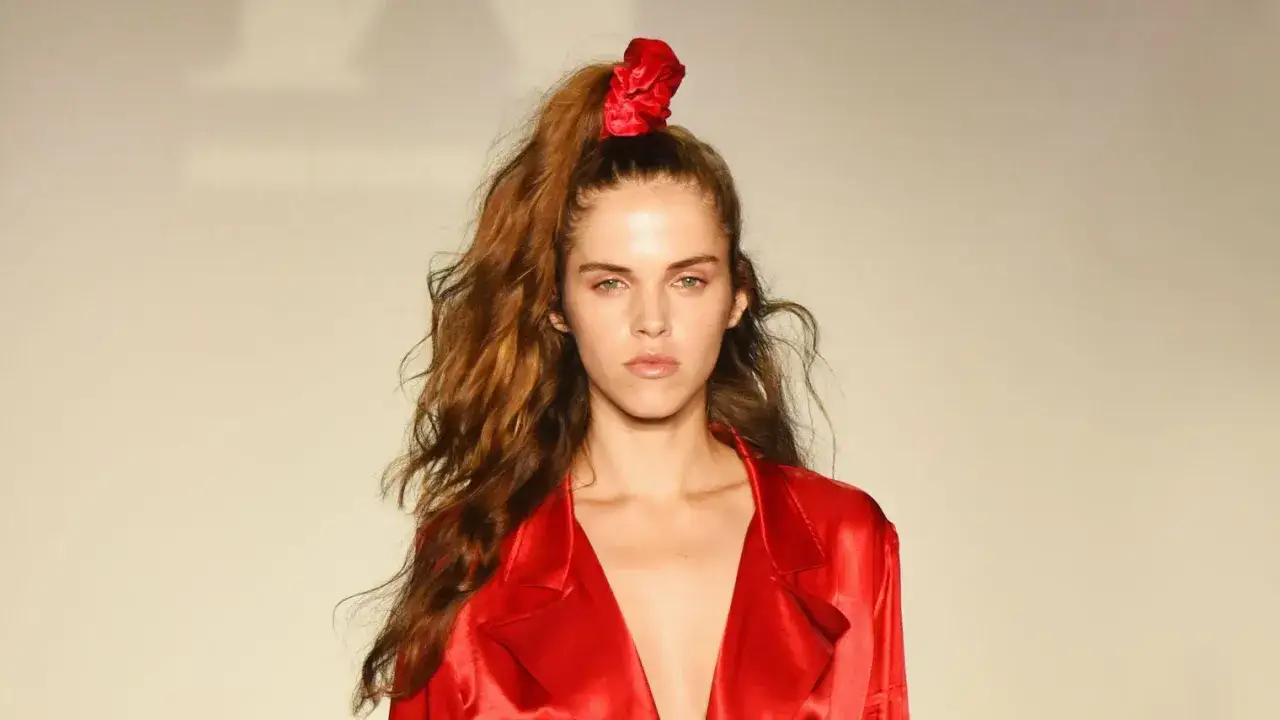 Modelo con un peinado alto y suelto, con un scrunchie rojo, evocando las 80s hairstyles.