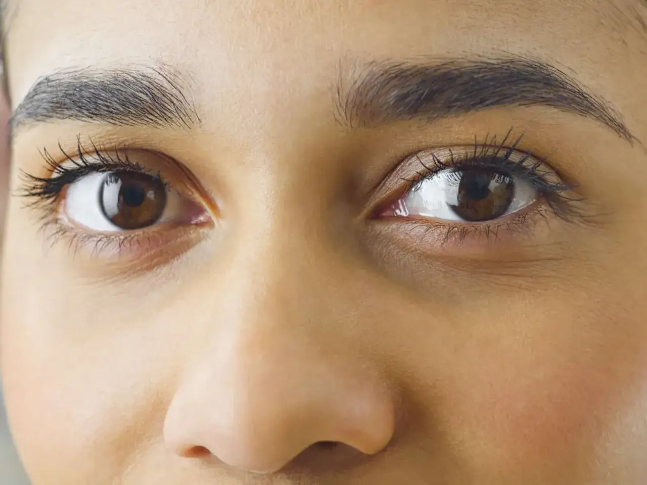 Ojos marrones y cejas definidas, perfectos para aprender como depilarse las cejas y lograr un look impecable.