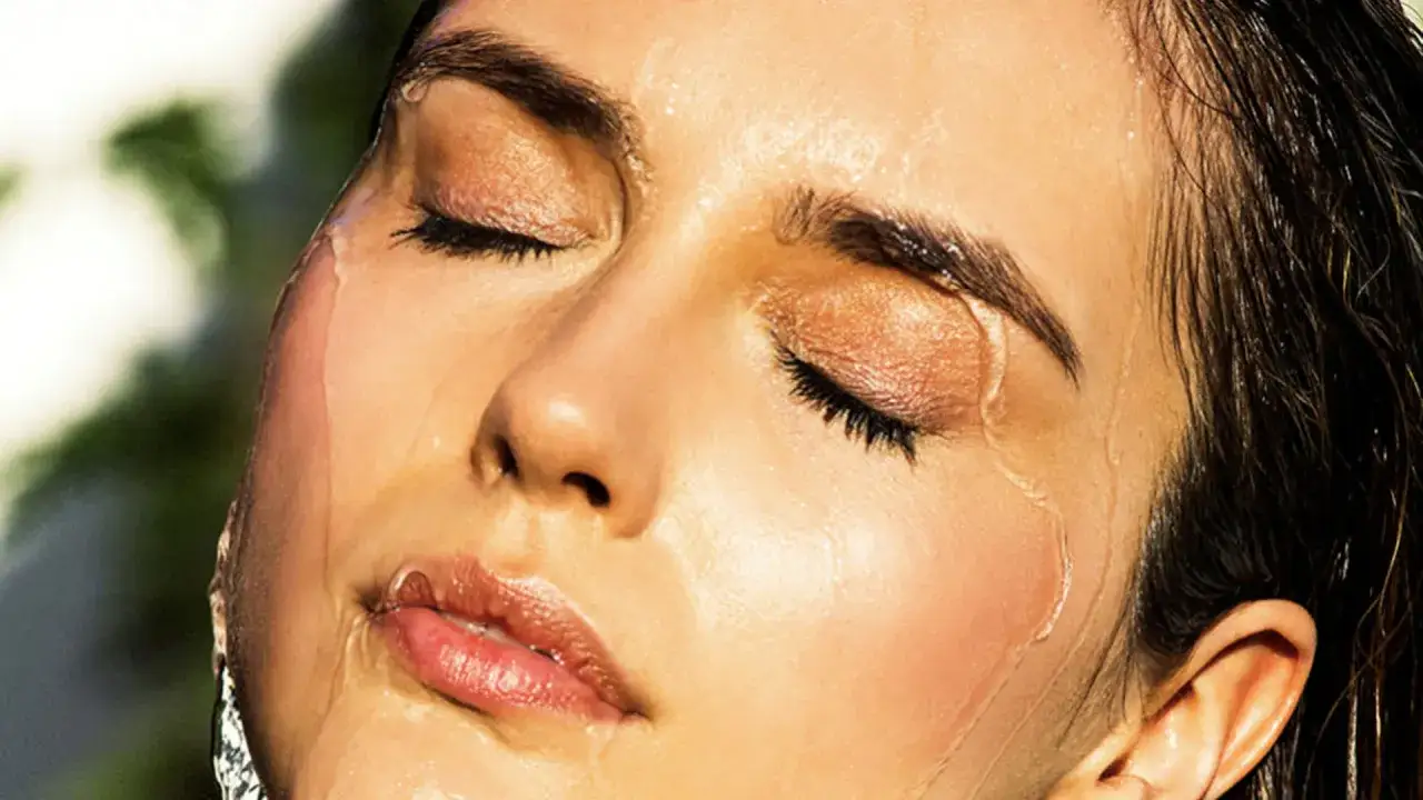 Rostro con maquillaje para ir a la playa, gotas de agua refrescando la piel.