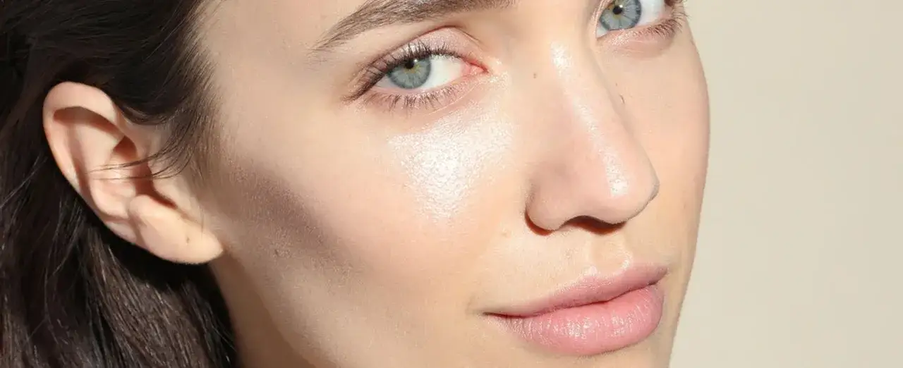 Piel luminosa y preparada para el maquillaje. Rostro de mujer con ojos azules y labios rosados, mostrando la preparación de la piel antes del maquillaje.