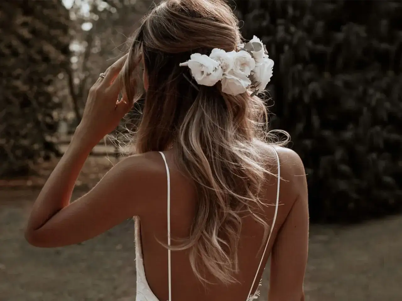 Novia con moño alto despeinado adornado con flores blancas, ideal para una boda de ensueño.
