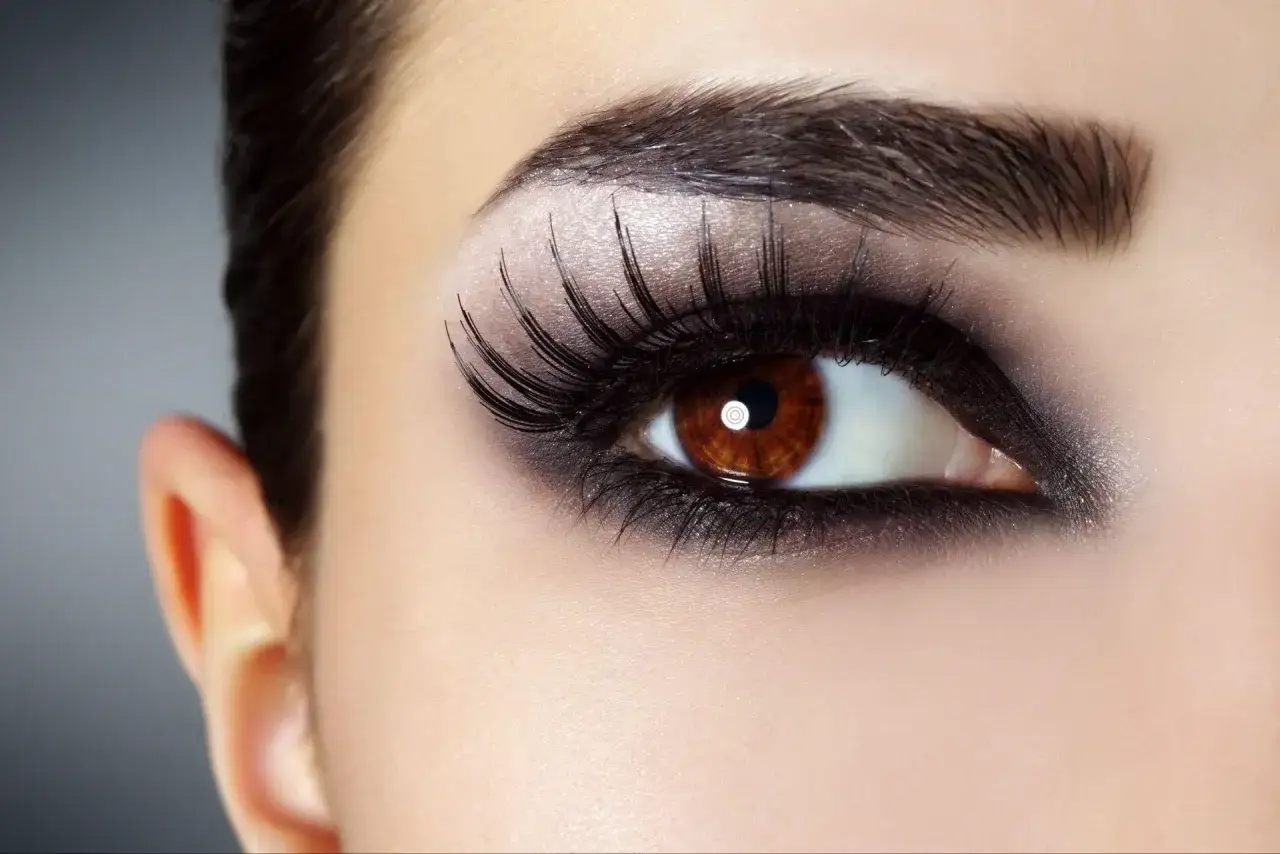 Ojo con maquillaje dramático, sombras negras ahumadas y pestañas postizas. Un look impactante para resaltar la mirada.