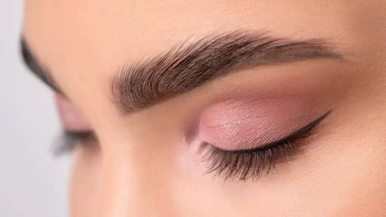 Ojo cerrado con sombra rosa, delineado fino y cejas separadas bien definidas.